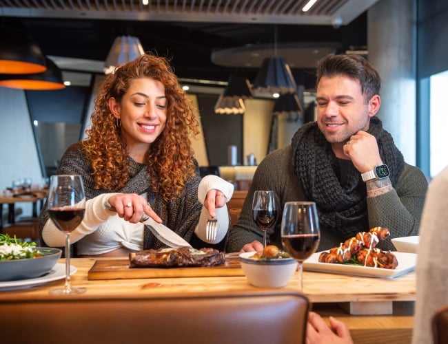 Couple sitting at a wooden table in a restaurant enjoying dinner