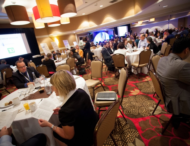 Individuals gathered around tables in a conference setting