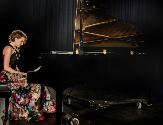 Sarah Hagen sits at a grand piano. 