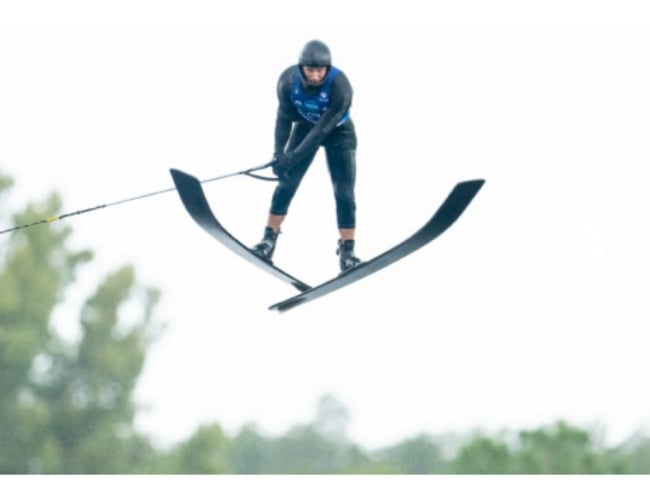 A professional waterski jumper soaring a distance of 70 m off a 1.8 m high jump