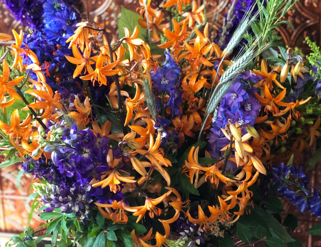 Purple and orange flower arrangement with wheat accents made at the Black Fox Flower Class