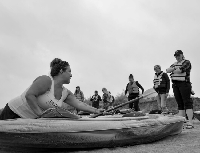 People standing around kayaks