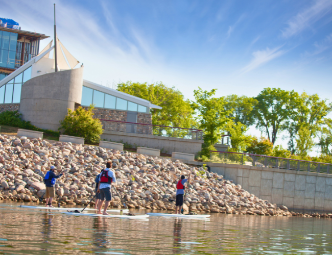 Three people on paddleboards going down the South Saskatchewan river at River Landing