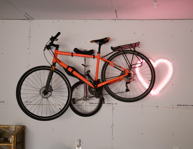 Bike up on a rack in a garage with a heart led sign behind it