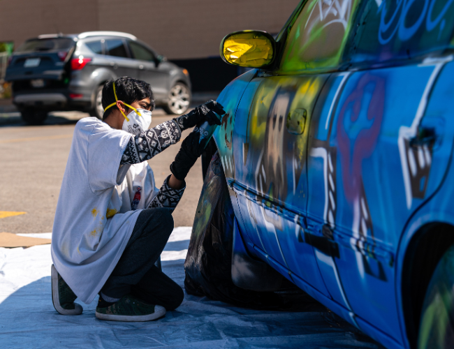 Person wearing a mask while spray painting a car