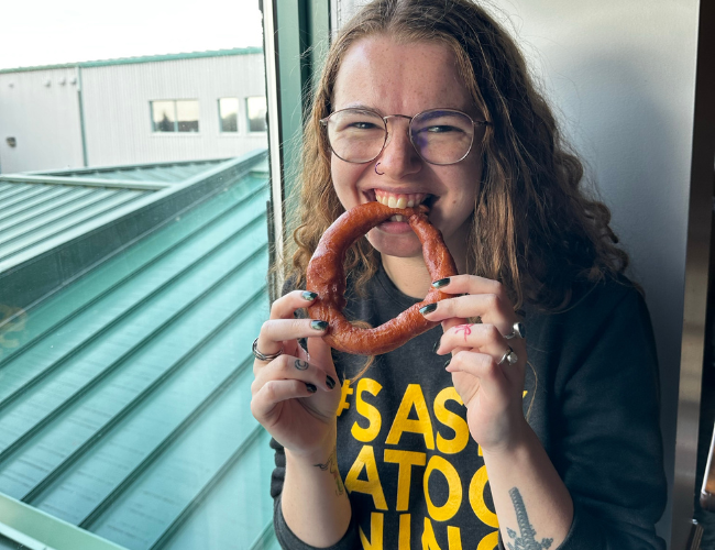 Person eating a spudnut beside a window