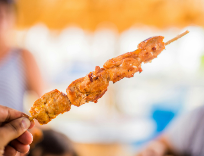 Person holding a bbq pork skewer