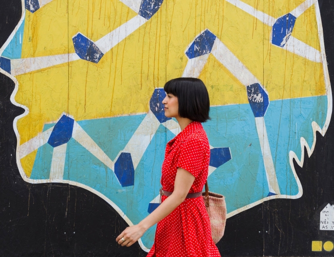 woman walking past a mural 