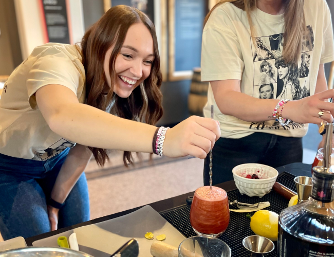 Female mixing cocktail that she created herself during Cocktail Class