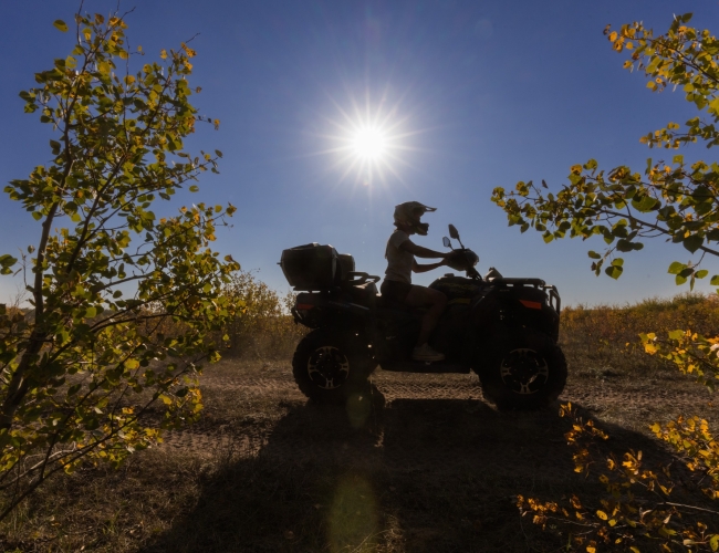 person on a quad on a trail with a sunny blue sky in the background