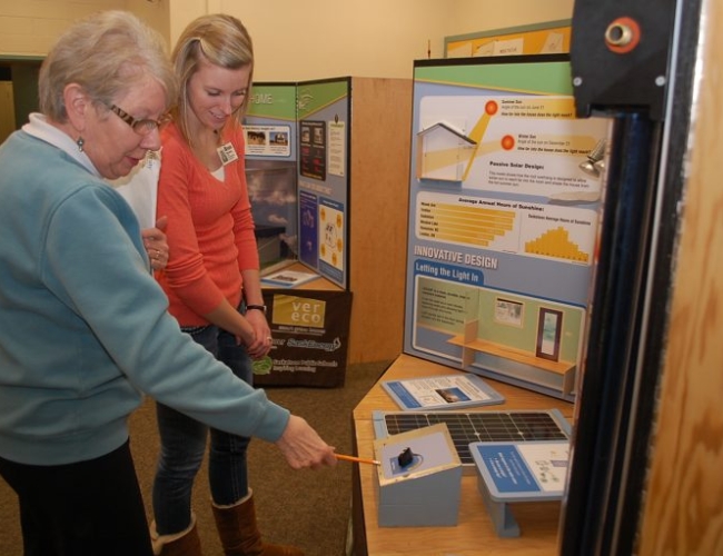 A museum guide and visitor look at a science demonstration display.