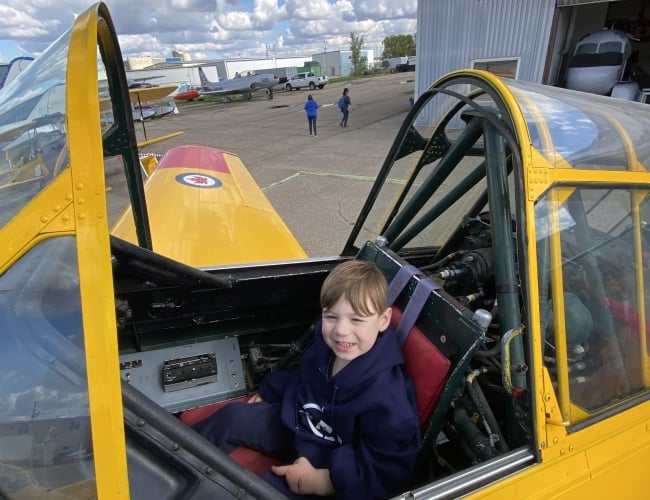 Future pilot seated at the flight controls of a vintage Harvard RCAF Training aircraft.