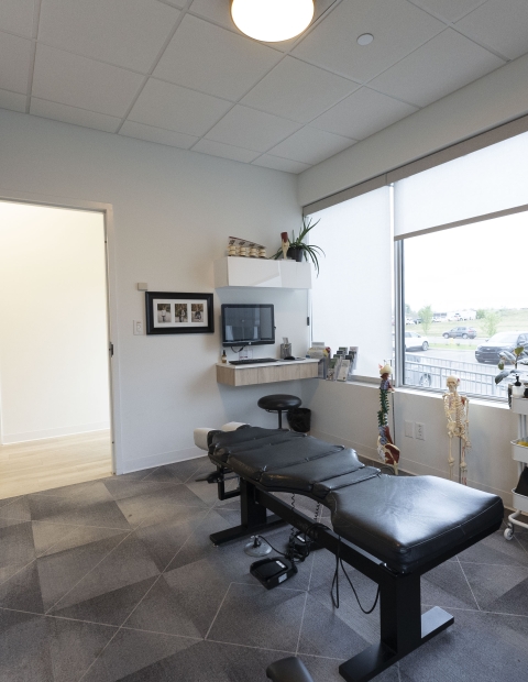 Interior of a chiropractors office with a desk and chair.